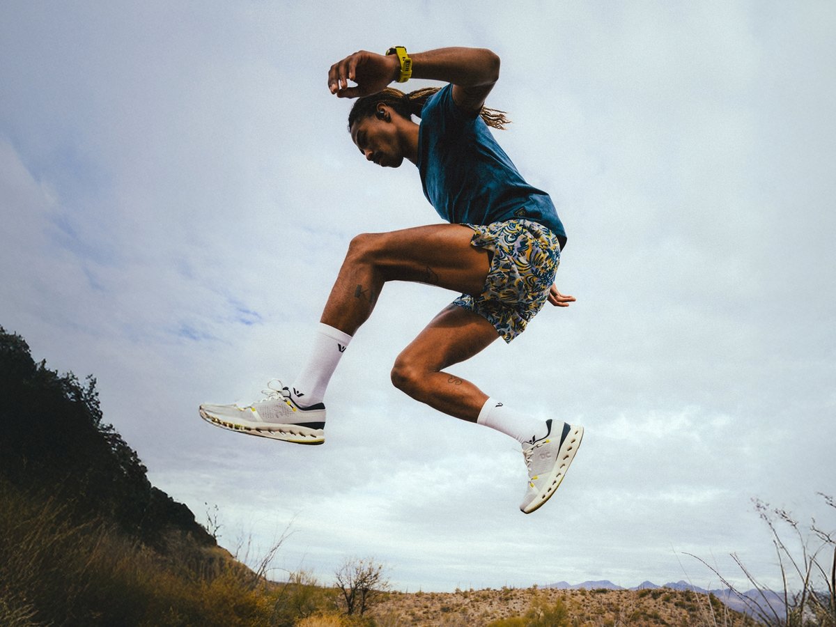 A man leaps into the air when running down a trail in the desert.