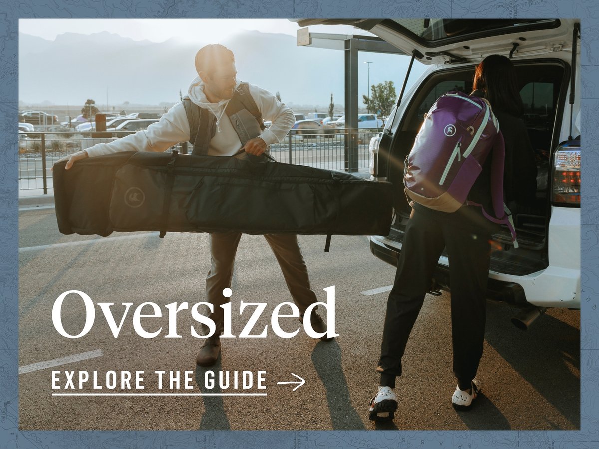 Two people are loading up a vehicle with bags. One person is attempting to put a very long ski bag into the car. The words, “Oversized, explore the guide” appear under them.