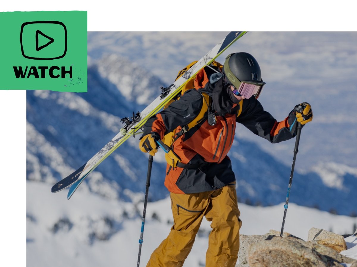 Skier climbs uphill with an epic mountain vista in the background. 